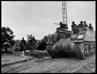 Un M7 Priest franchit l'Aisne tandis que des civils consolident la chaussée